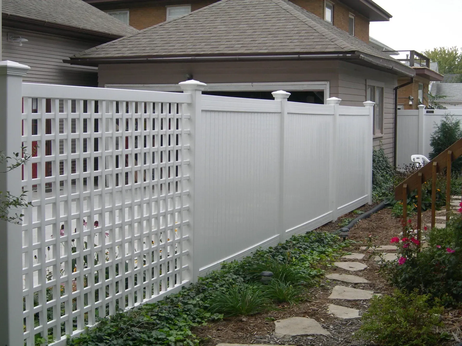 A white fence with a lattice design is in front of a house