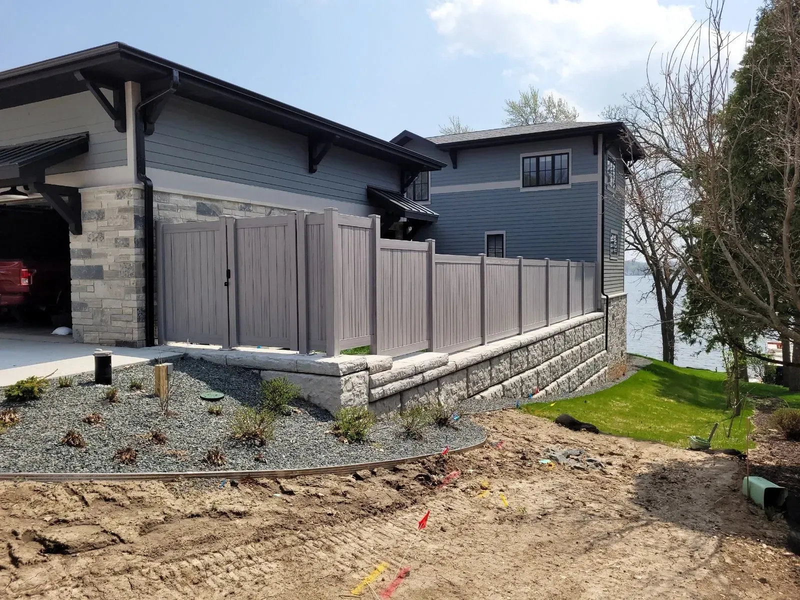 A house with a fence and a garage next to a body of water.