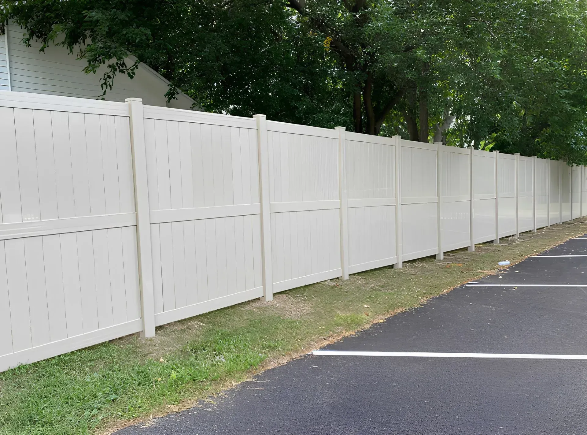 A white fence is along the side of a parking lot