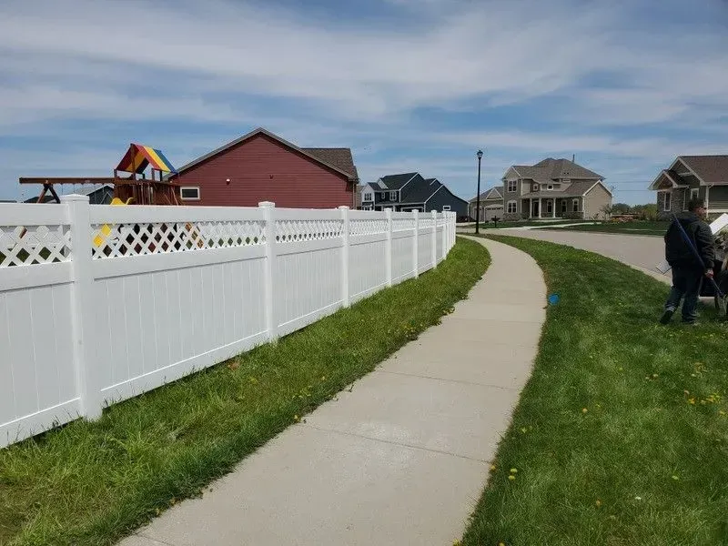 A white fence along a sidewalk in a residential neighborhood.