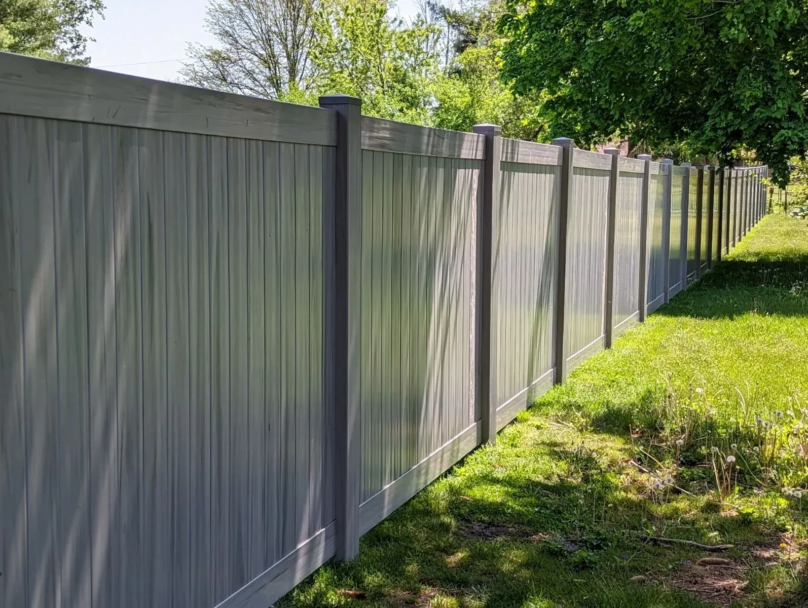 A gray fence is sitting in the middle of a lush green field.