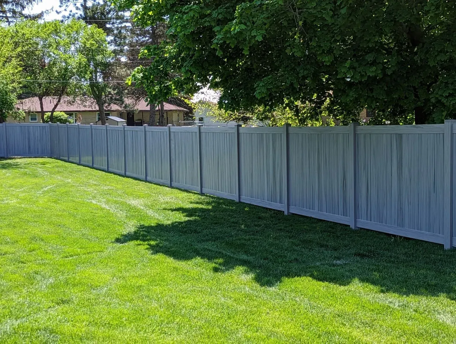 A long white fence surrounds a lush green lawn.