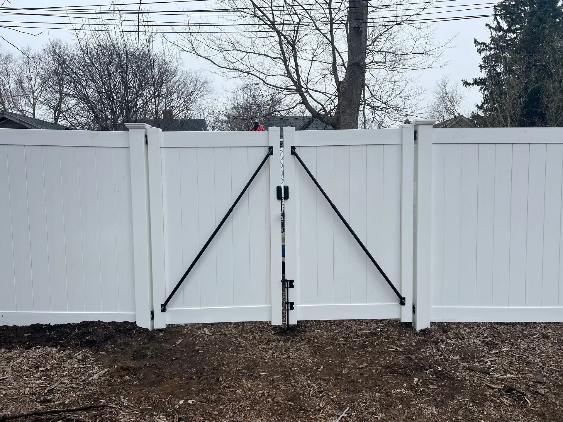 A white fence with a black gate attached to it