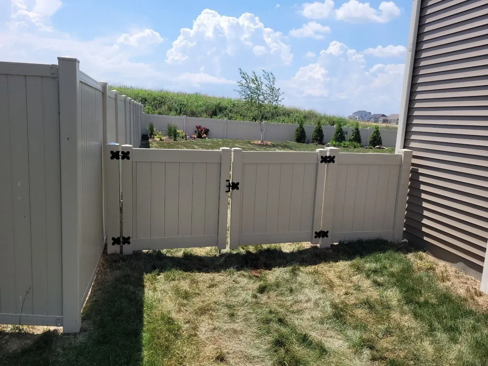 A white fence with a gate in the backyard of a house.