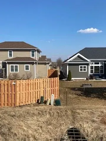 There is a wooden fence in the middle of the yard between two houses.