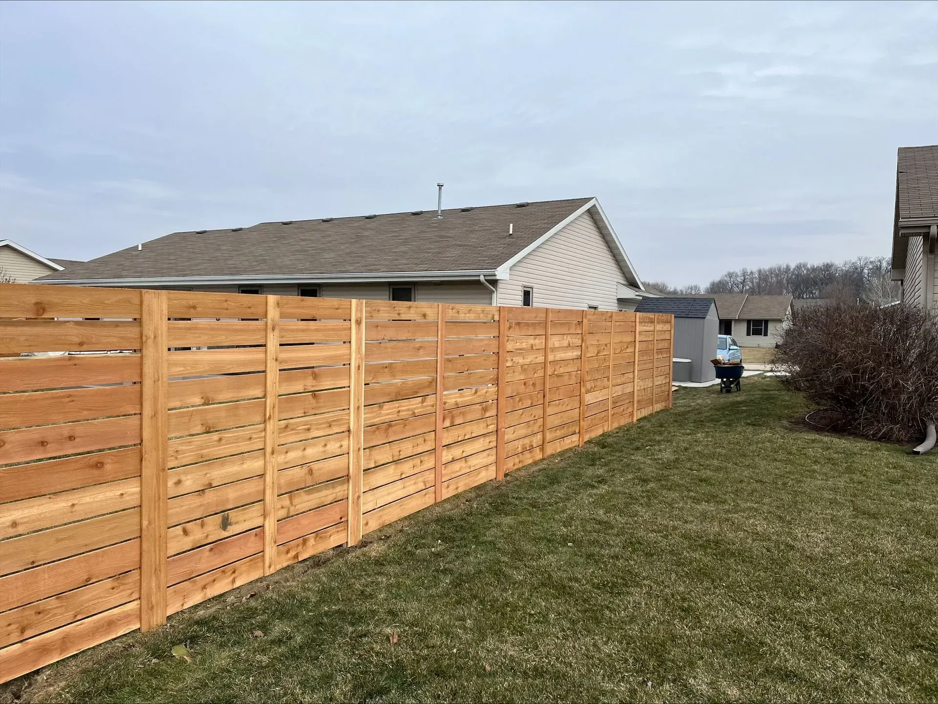 A wooden fence is in the backyard of a house.