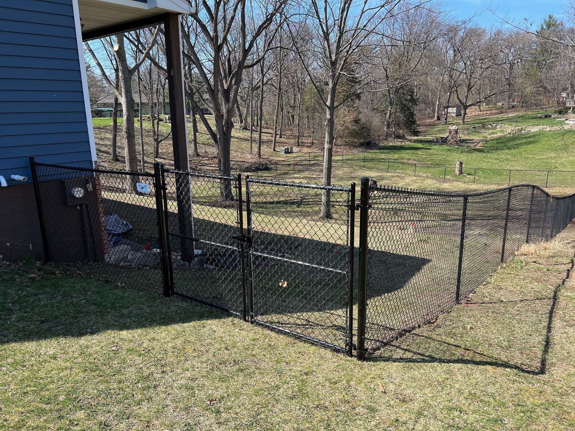 A black chain link fence is in the backyard of a house.