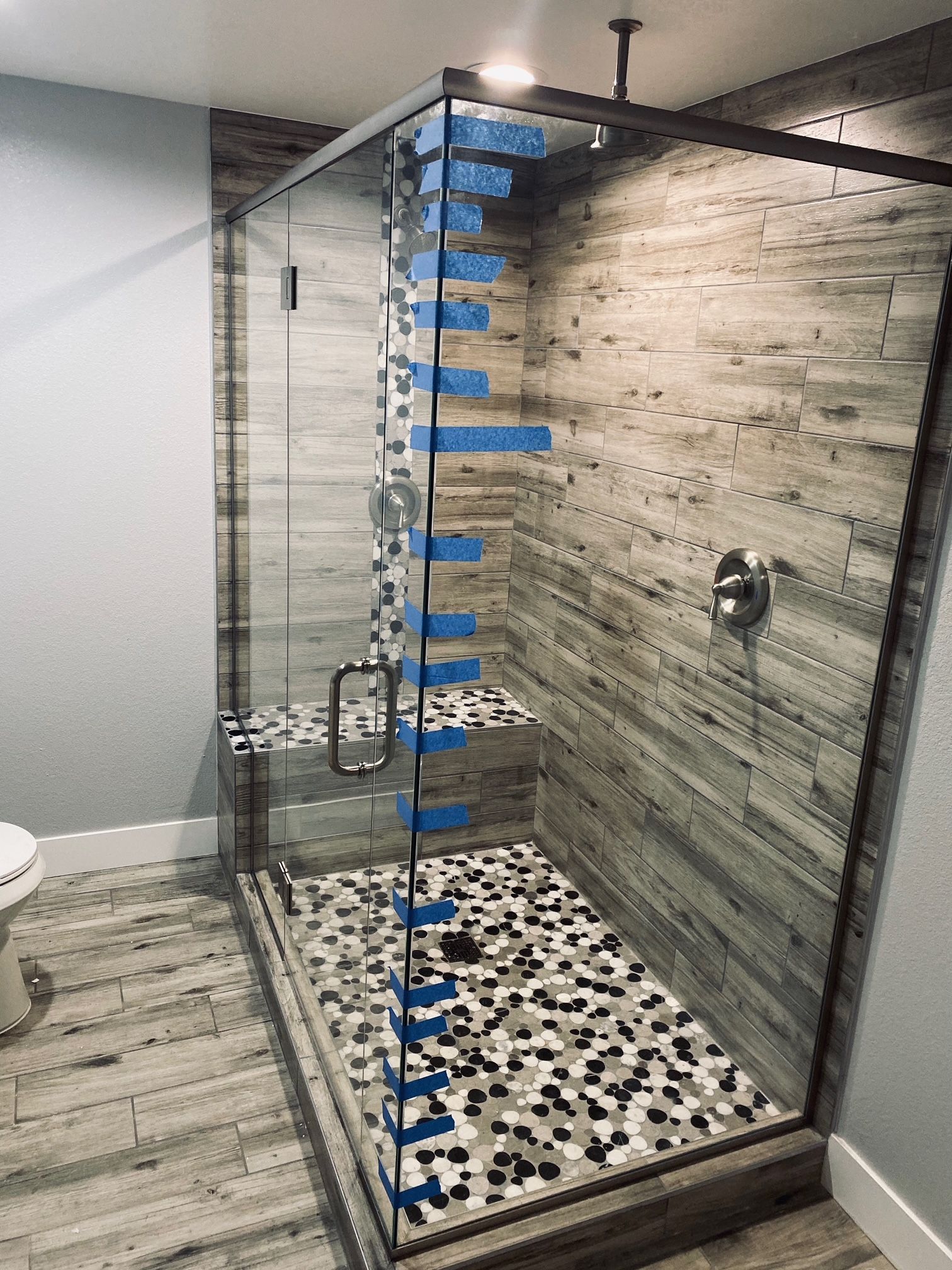 Modern shower with glass enclosure, tiled walls and floor, and bench seat.