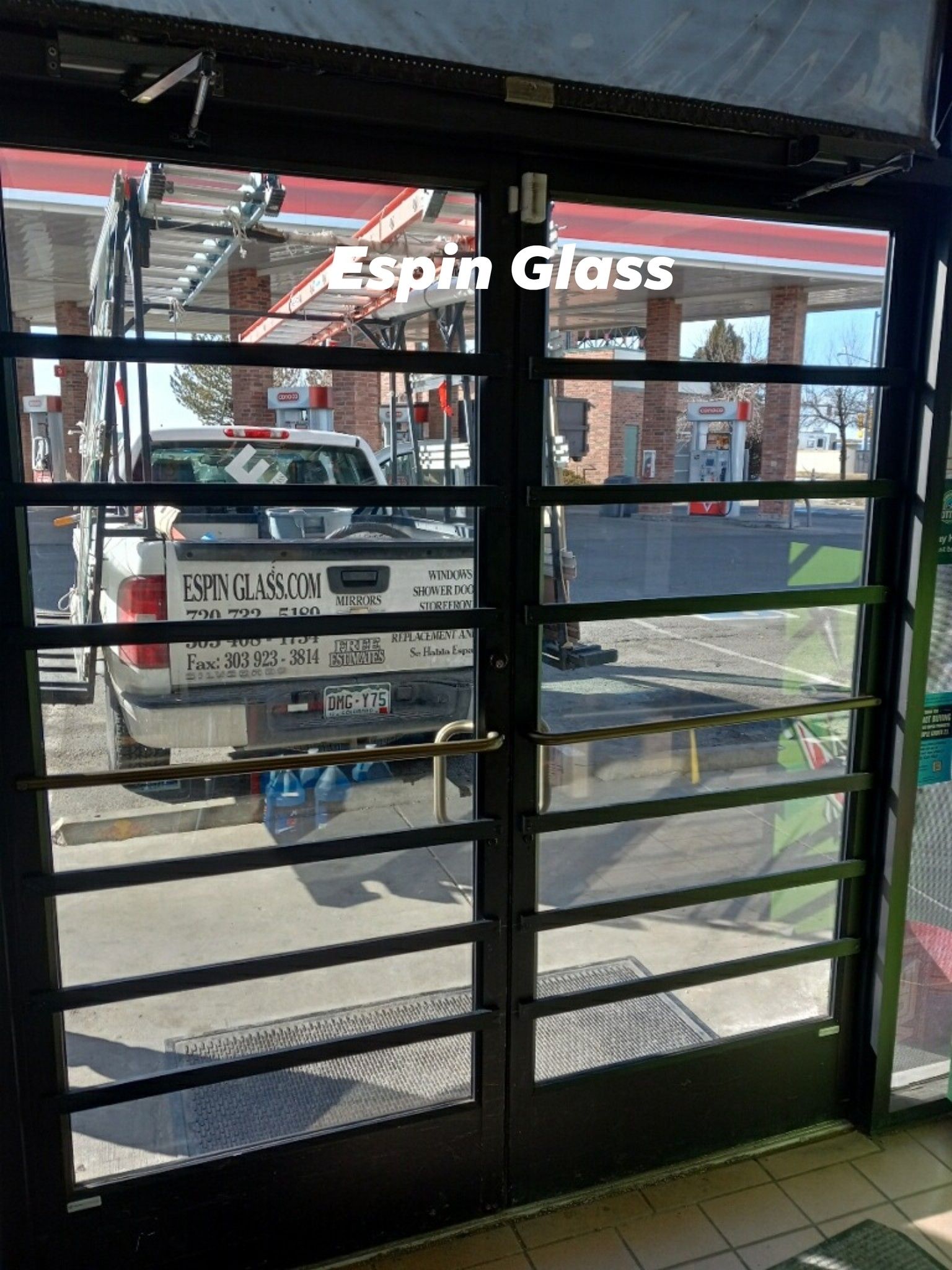 Double glass doors with black horizontal bars; view of a truck and a building outside.