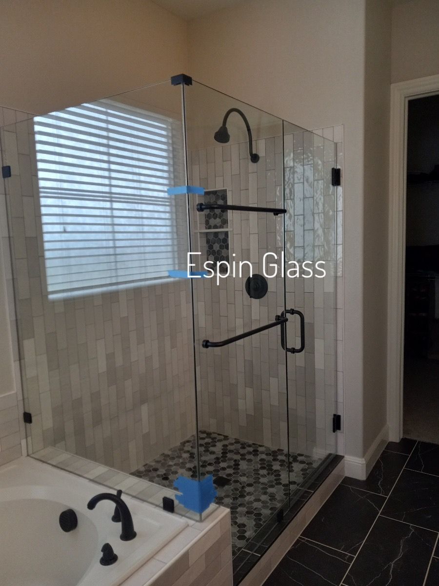 Glass shower enclosure with black fixtures and pebble floor.