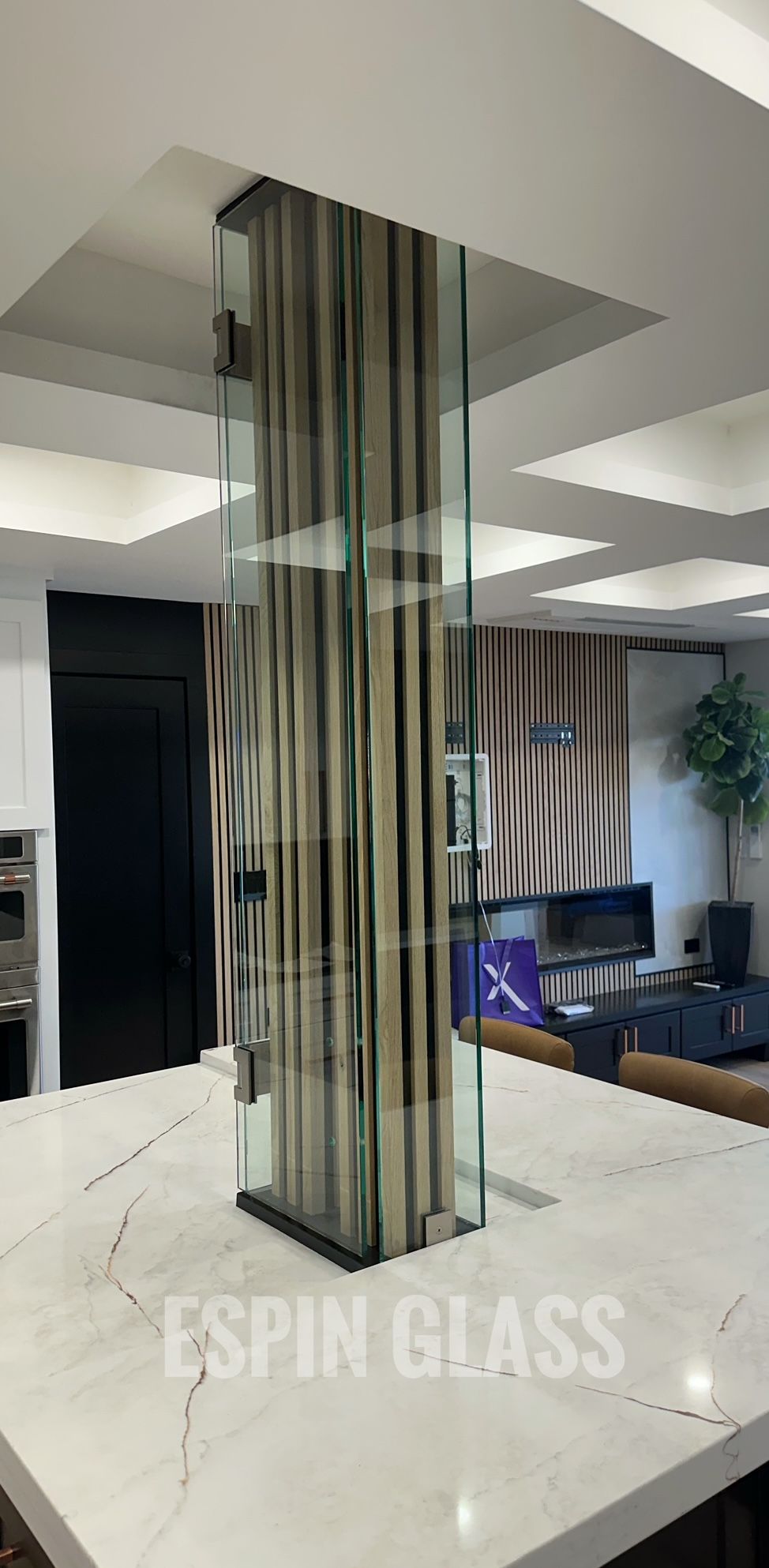 A glass pillar with curtains inside stands on a white countertop in a modern kitchen.