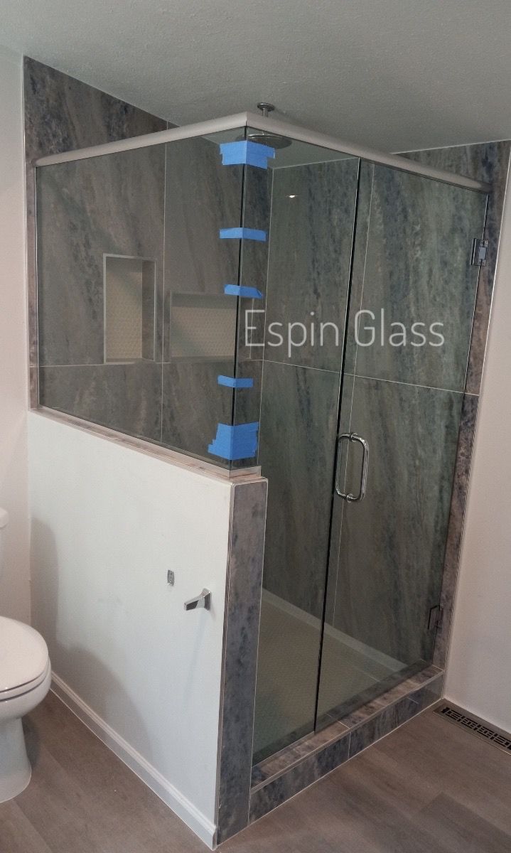 Corner shower enclosure with glass doors, tiled walls, and a toilet in a modern bathroom.