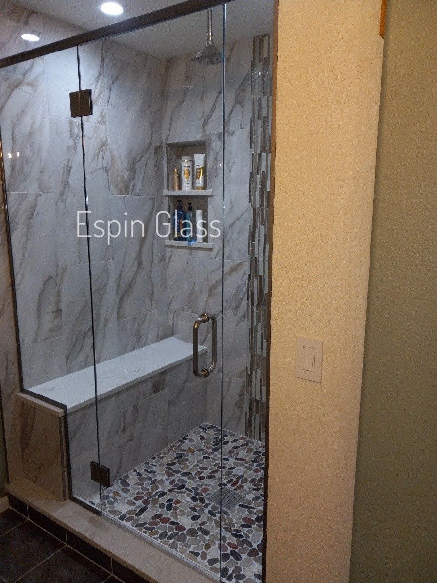 Glass shower enclosure with built-in bench and pebble floor.