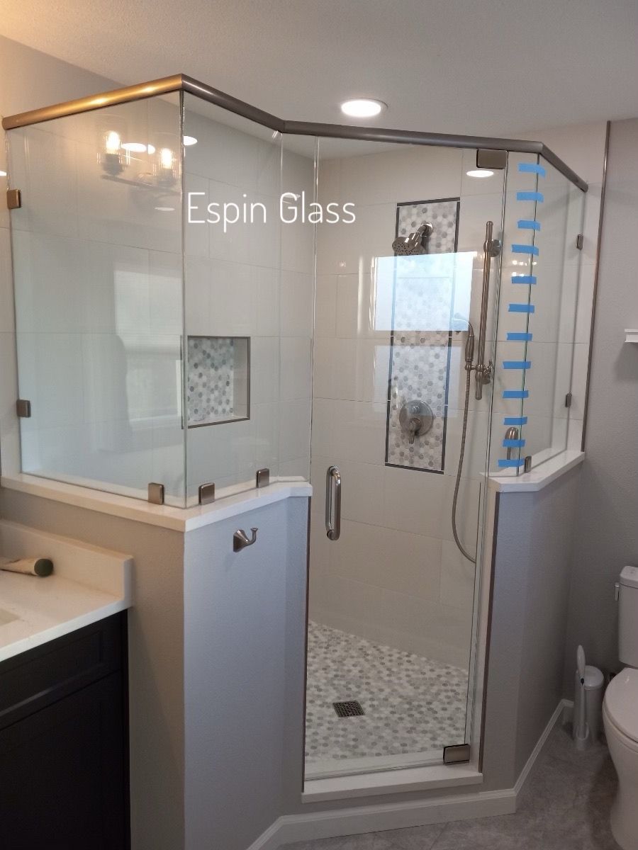 Glass shower enclosure in a bathroom with white and gray tones.