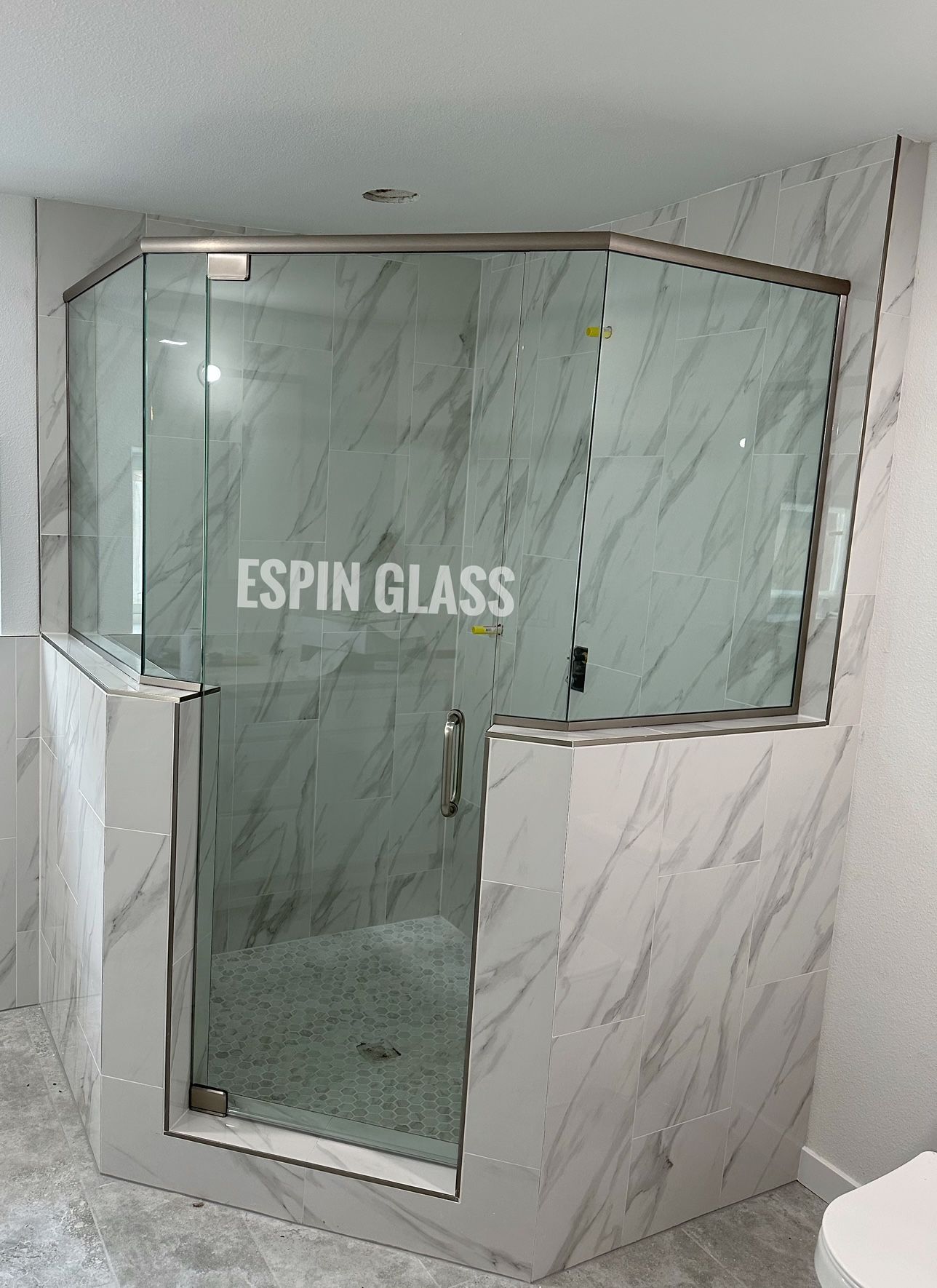 Glass shower enclosure with marble walls, door and silver hardware.