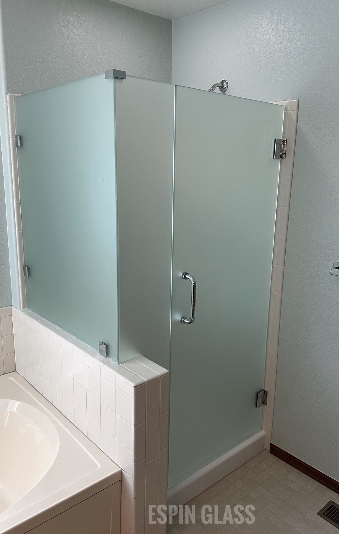 Frosted glass shower enclosure in a bathroom with white trim.