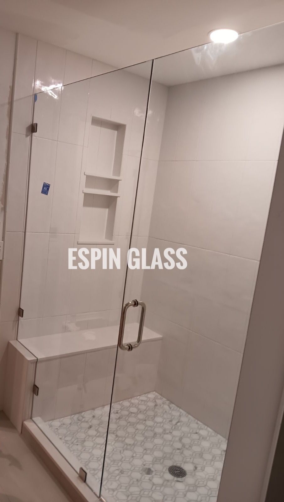 Glass shower enclosure with white tile, built-in bench, and shelves.