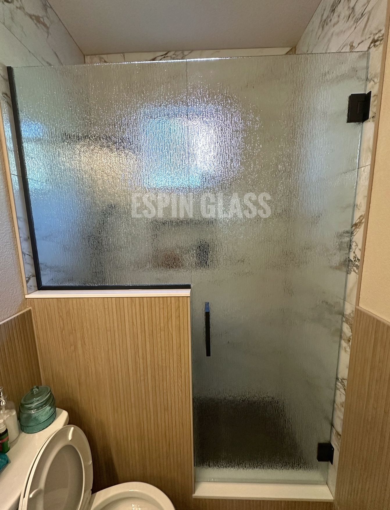 Textured glass shower enclosure with black hardware in a bathroom.