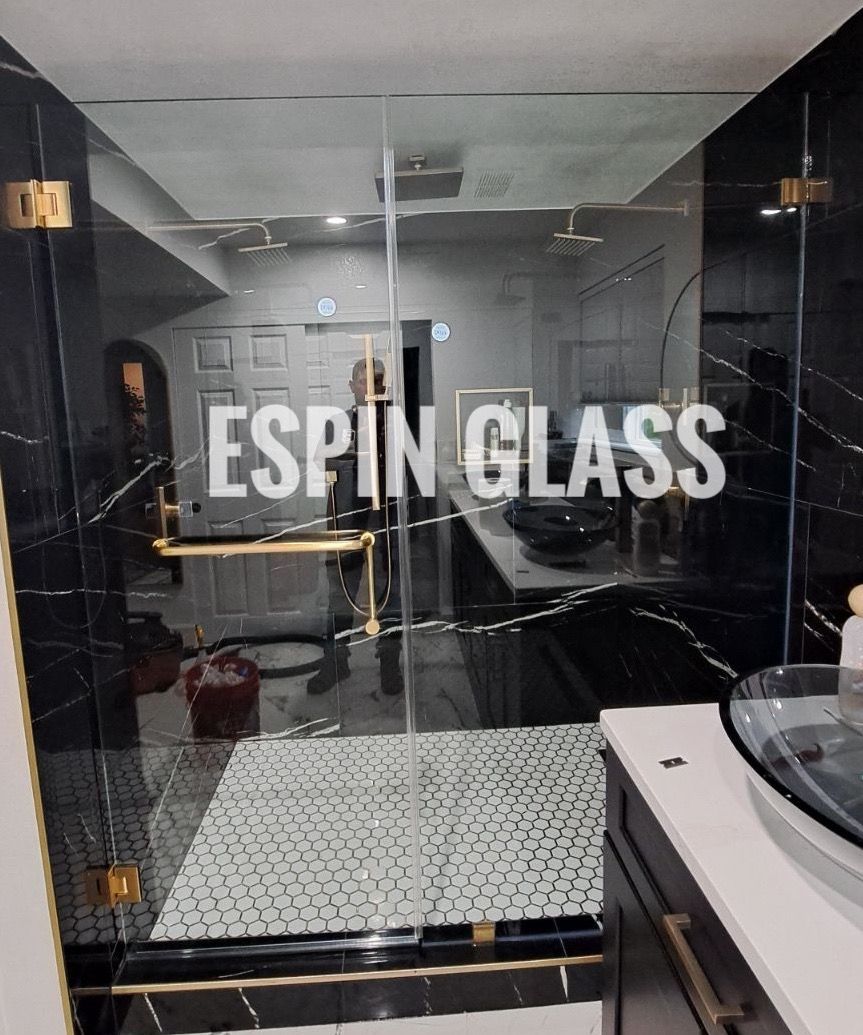 Bathroom with glass shower door; black marble walls, gold fixtures, white text 