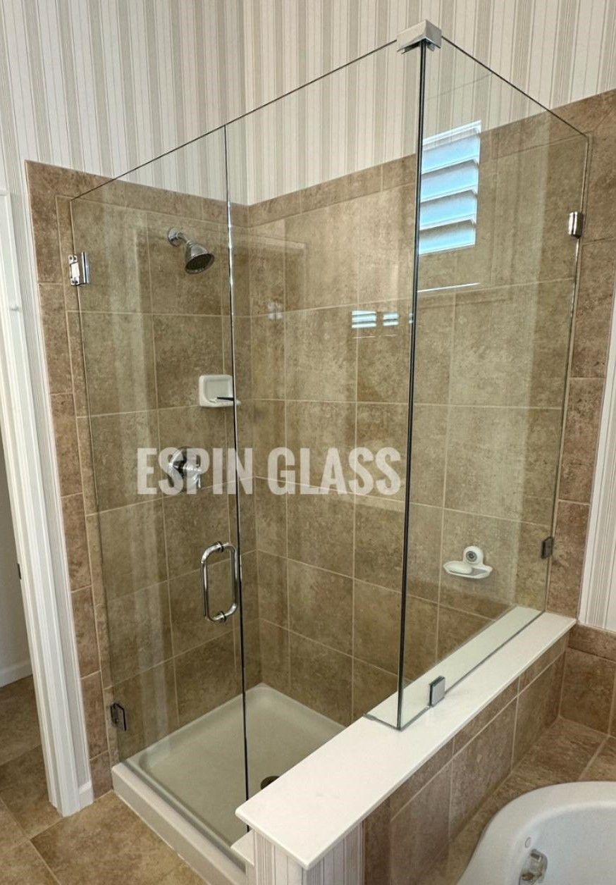 Glass shower enclosure with chrome hardware in a tiled bathroom.