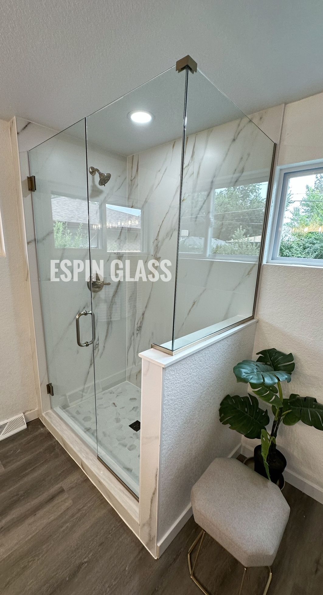 Modern shower with glass doors, white marble tile, chrome hardware, and a small window.