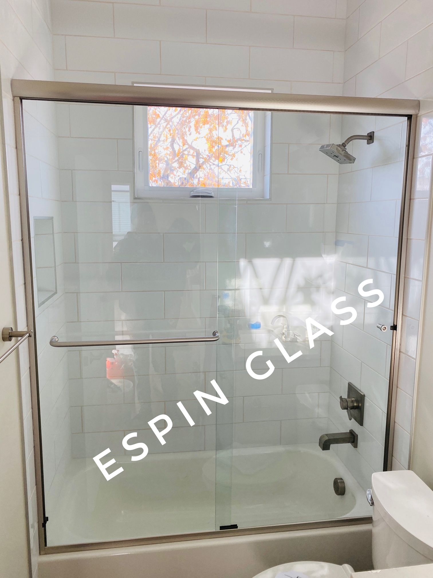Bathroom with glass shower door, white subway tile, and stainless steel fixtures.