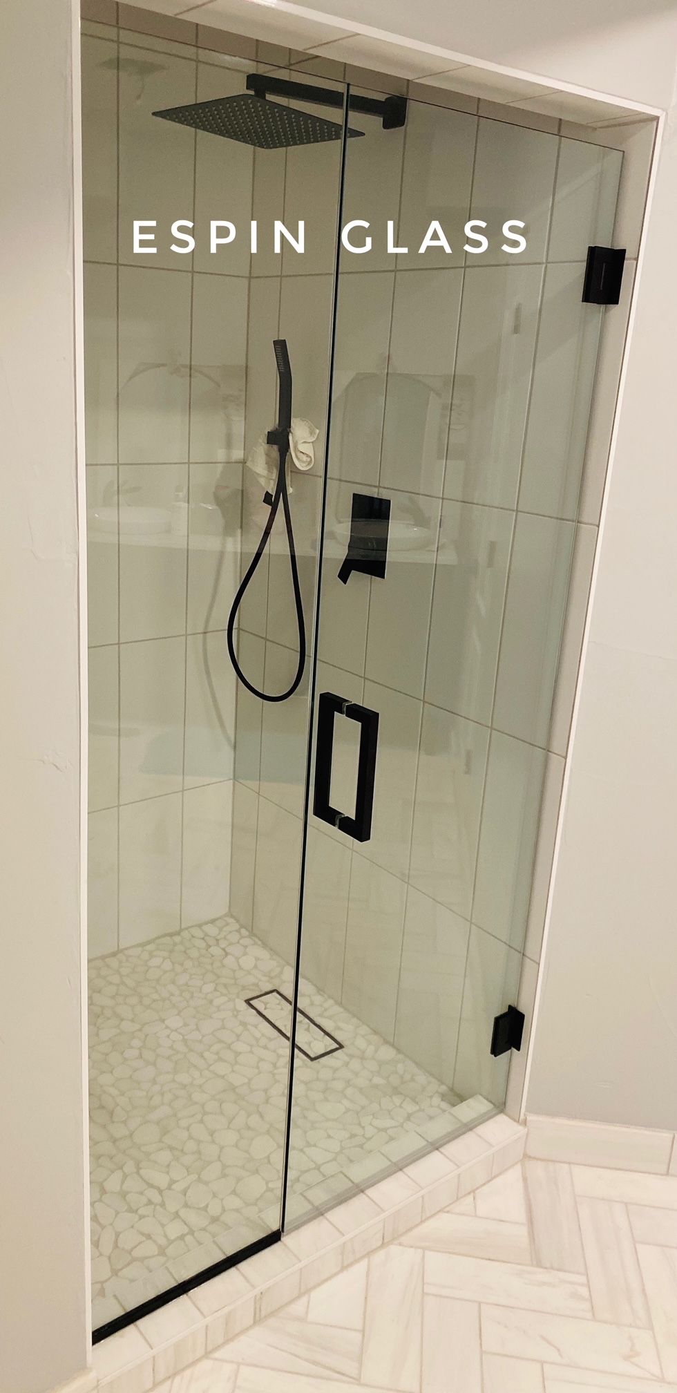 Modern shower enclosure with black fixtures, clear glass door, and tiled walls and floor.