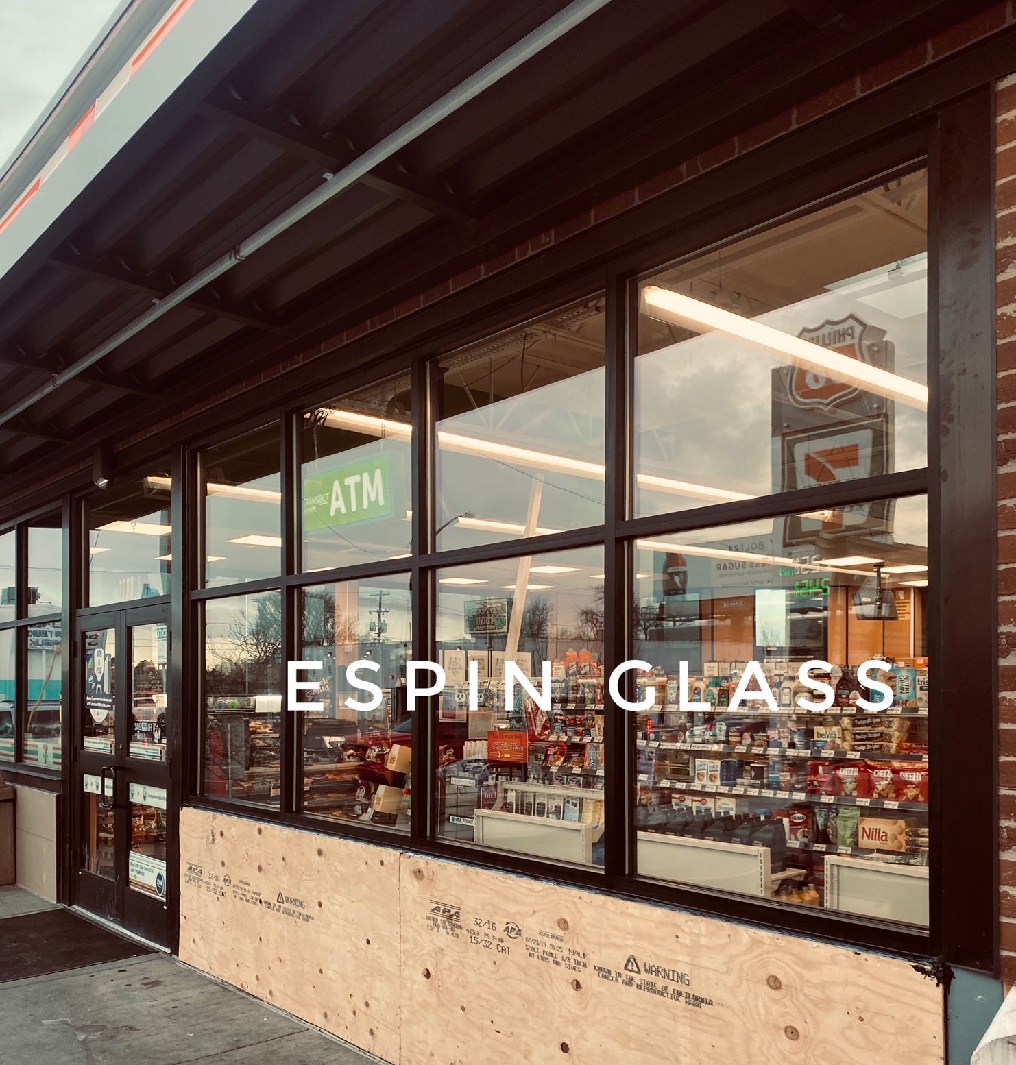 Exterior view of a convenience store with large windows, the text 