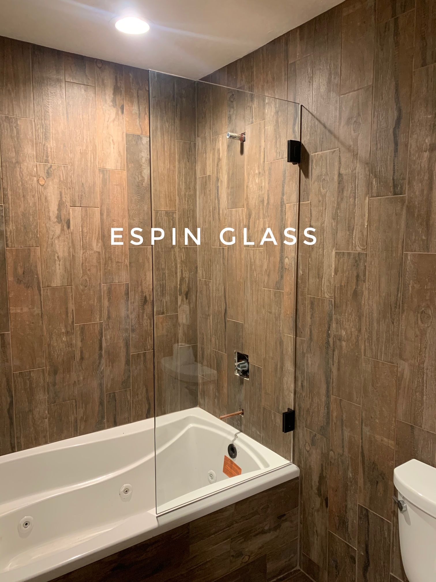 Glass shower enclosure with dark hardware in a bathroom with tile walls.