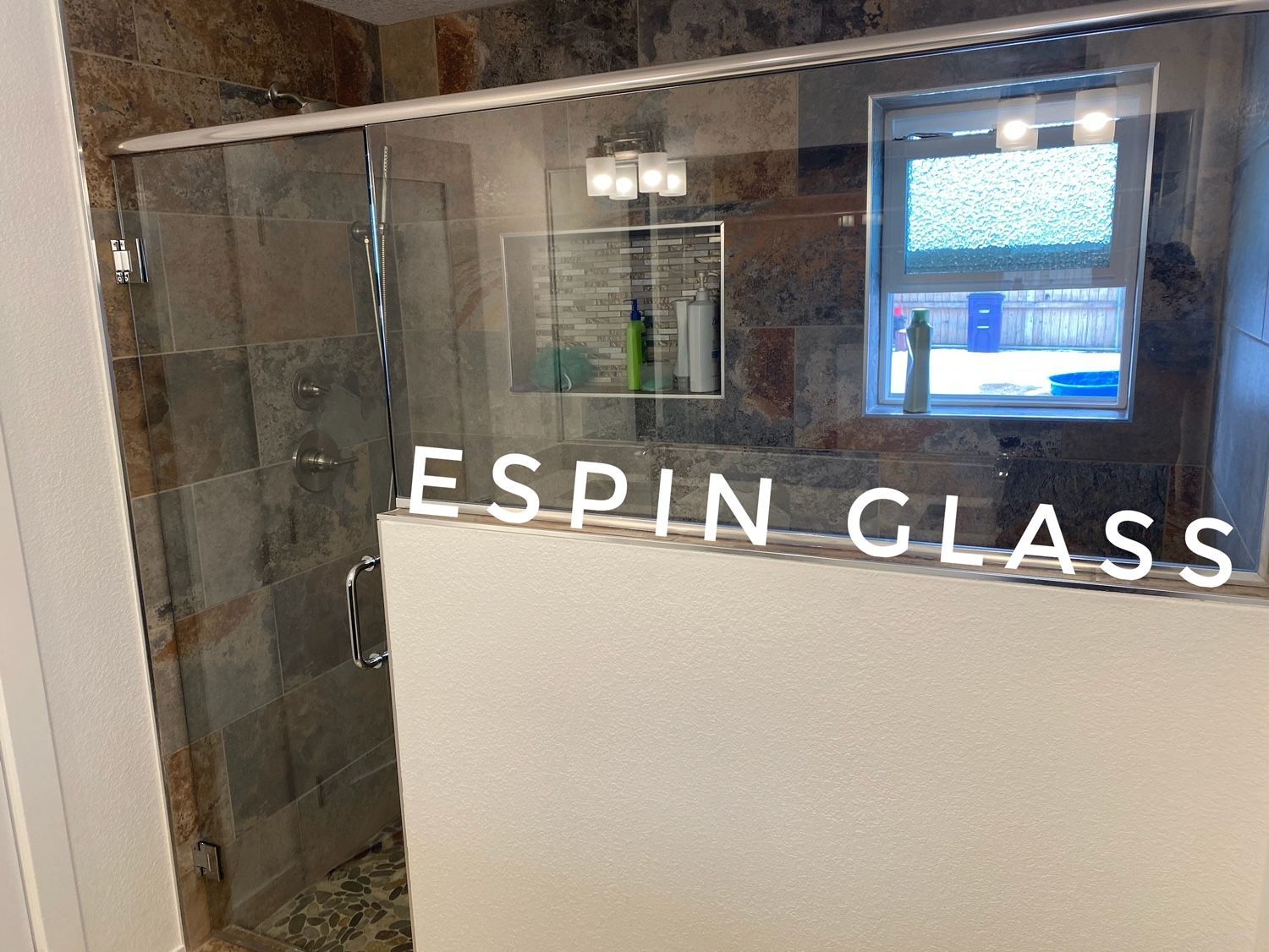 Shower with clear glass door, stone tile walls, and the words 