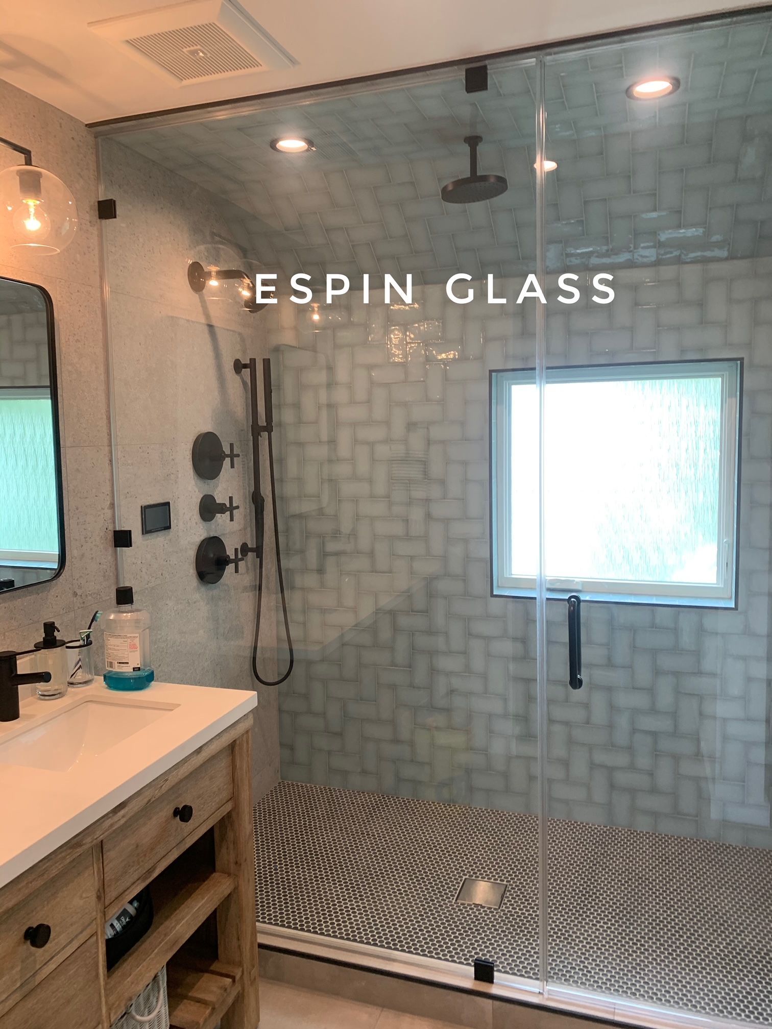 Bathroom with glass shower, black fixtures, patterned tile, and vanity.