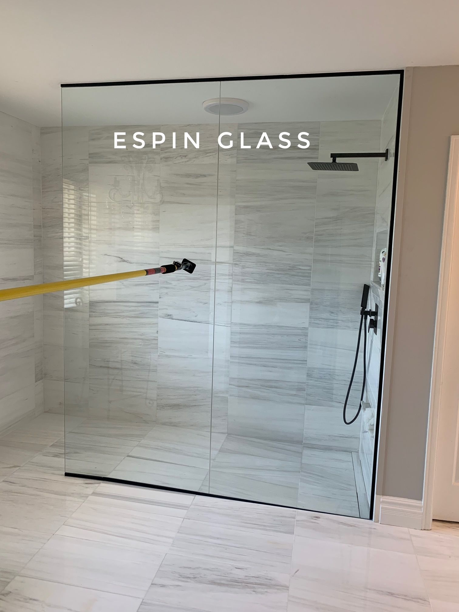 Modern shower enclosure with black trim and fixtures, clear glass, and gray tile walls.
