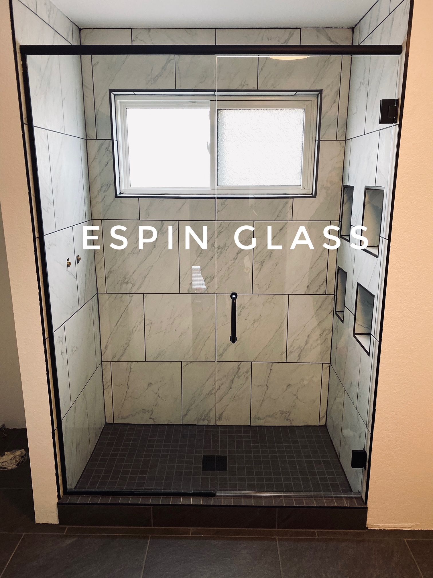 Frameless glass shower enclosure with black hardware and tiled walls.