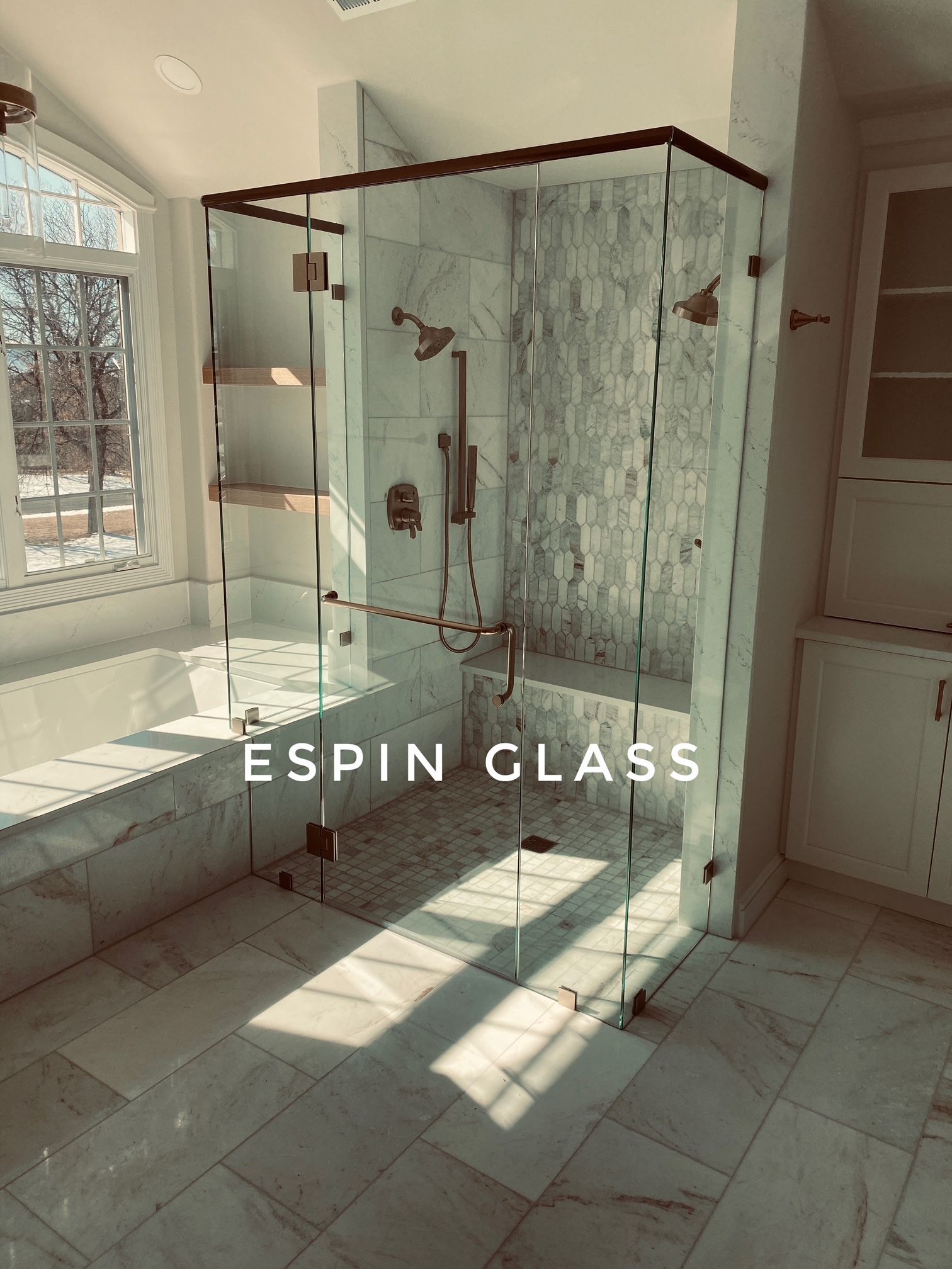Spacious bathroom with a glass shower, marble tile, and gold fixtures; text 