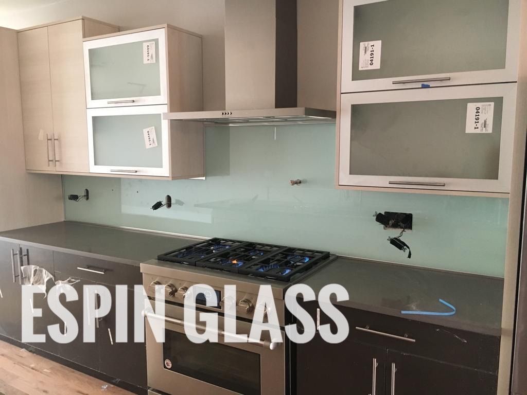 Modern kitchen with gray cabinets, a gas stove, and a light blue glass backsplash.