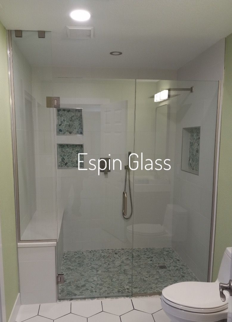 Glass shower enclosure with white walls and a toilet in a bathroom.