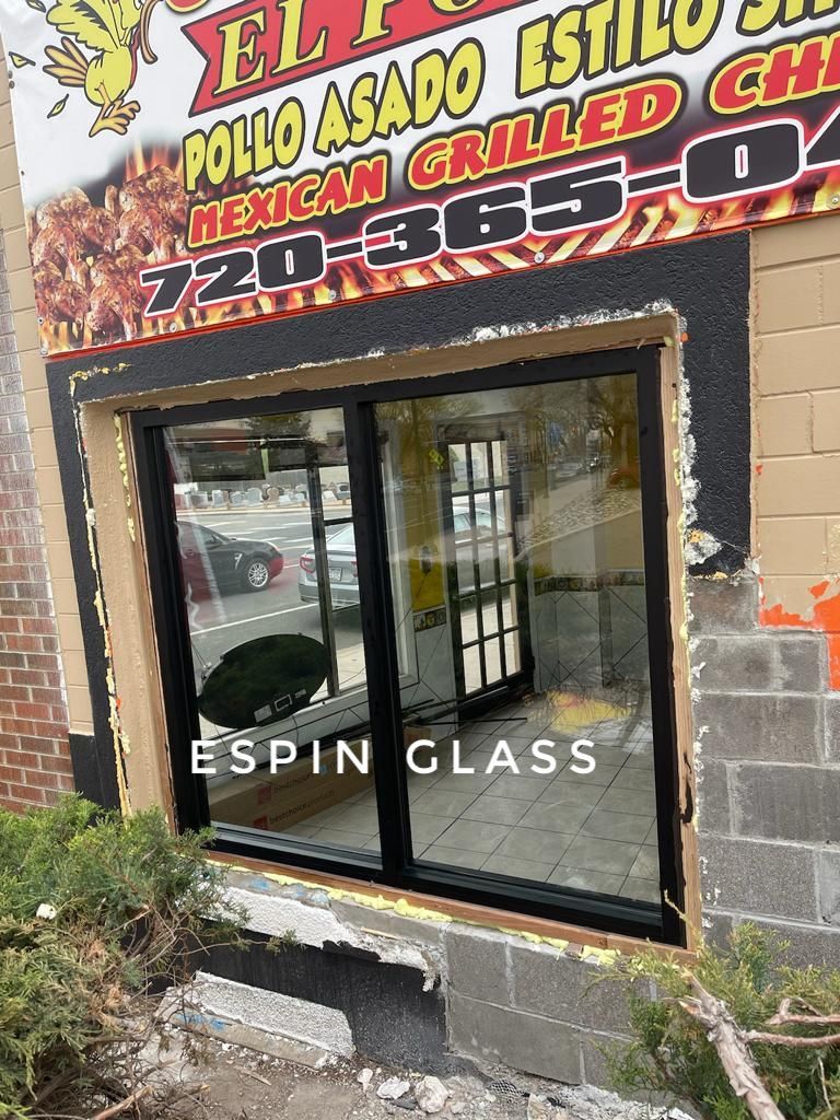 Exterior view of a restaurant with new glass sliding doors, black frames, and a sign above.
