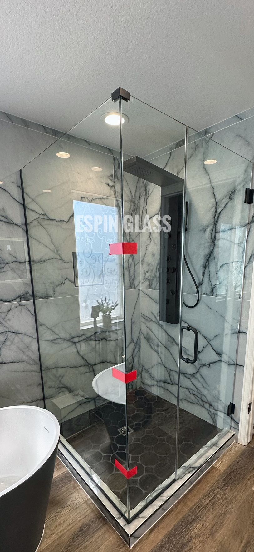 Modern bathroom with a glass shower and marble walls.