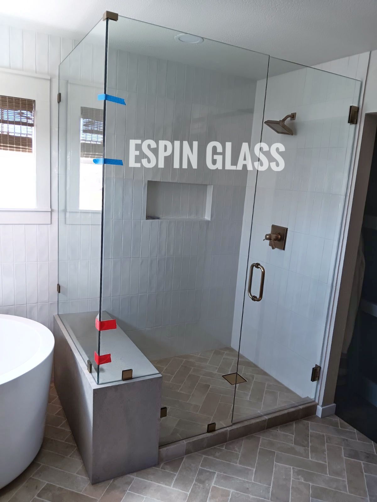 Frameless glass shower with a bench. Neutral-toned tile and fixtures.