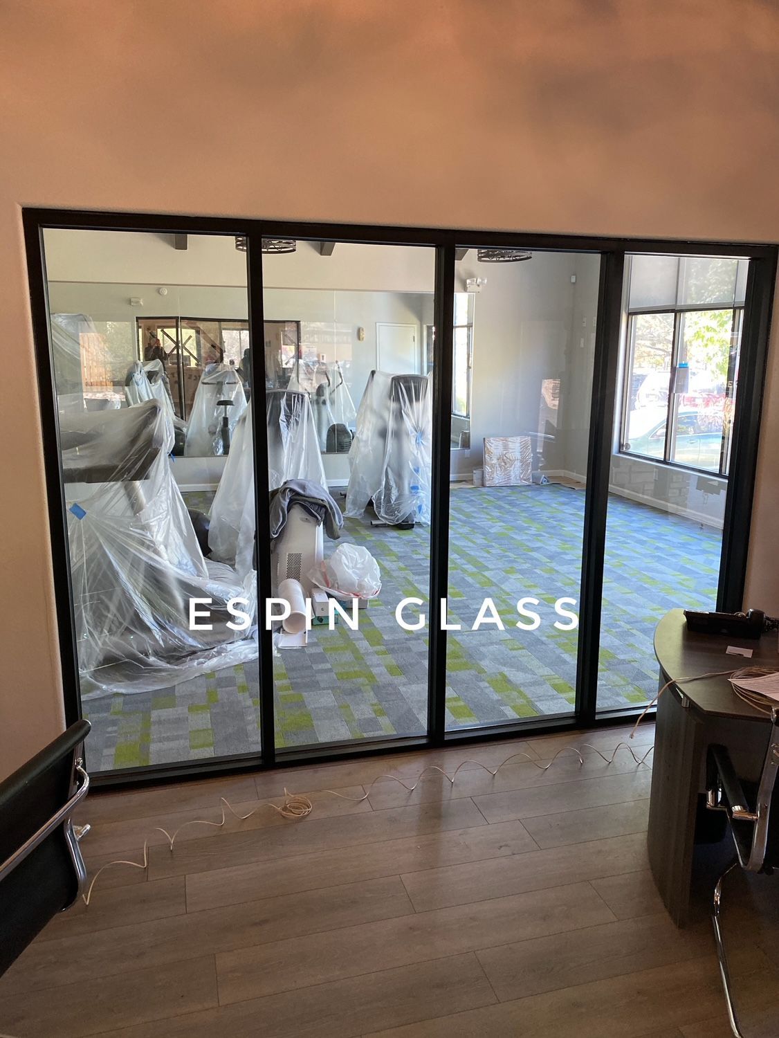 Glass wall with black frames, revealing a gym; the wall says 