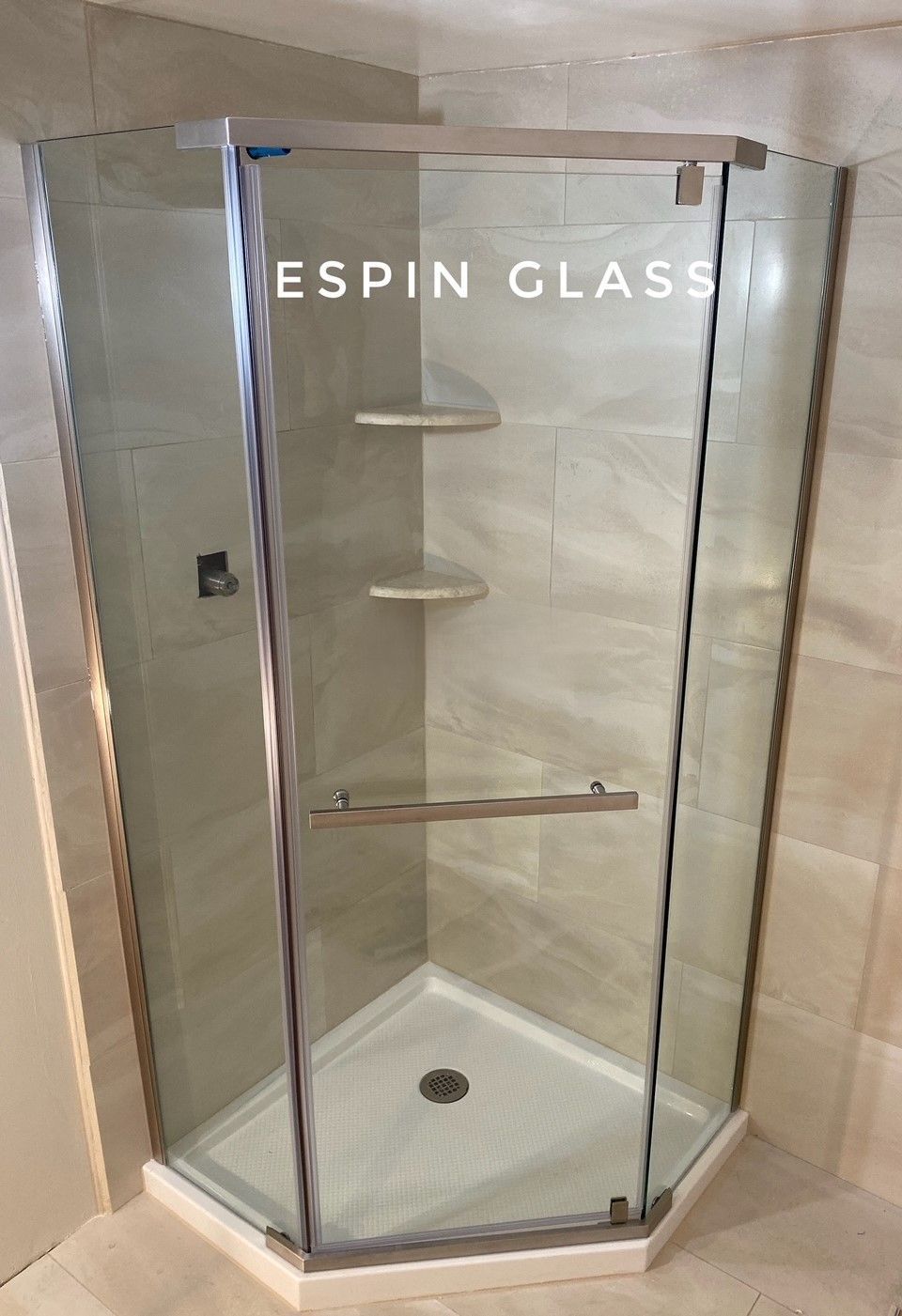 Frameless glass shower with corner entry, neutral tile walls, and built-in shelves.