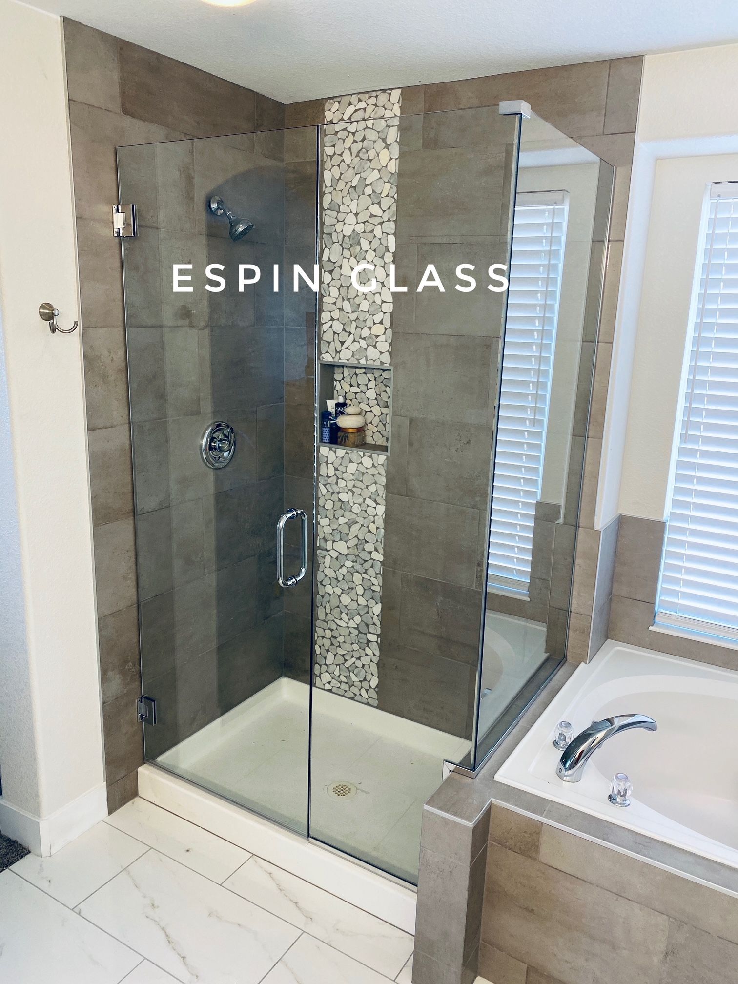 A modern bathroom with a glass shower enclosure, neutral tile, and a built-in bathtub.