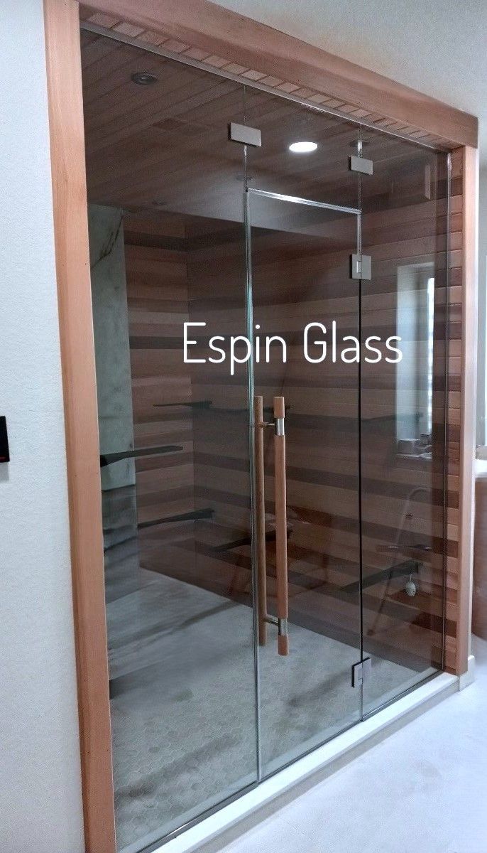 Glass shower enclosure with wooden frame and door; interior with wood paneling.