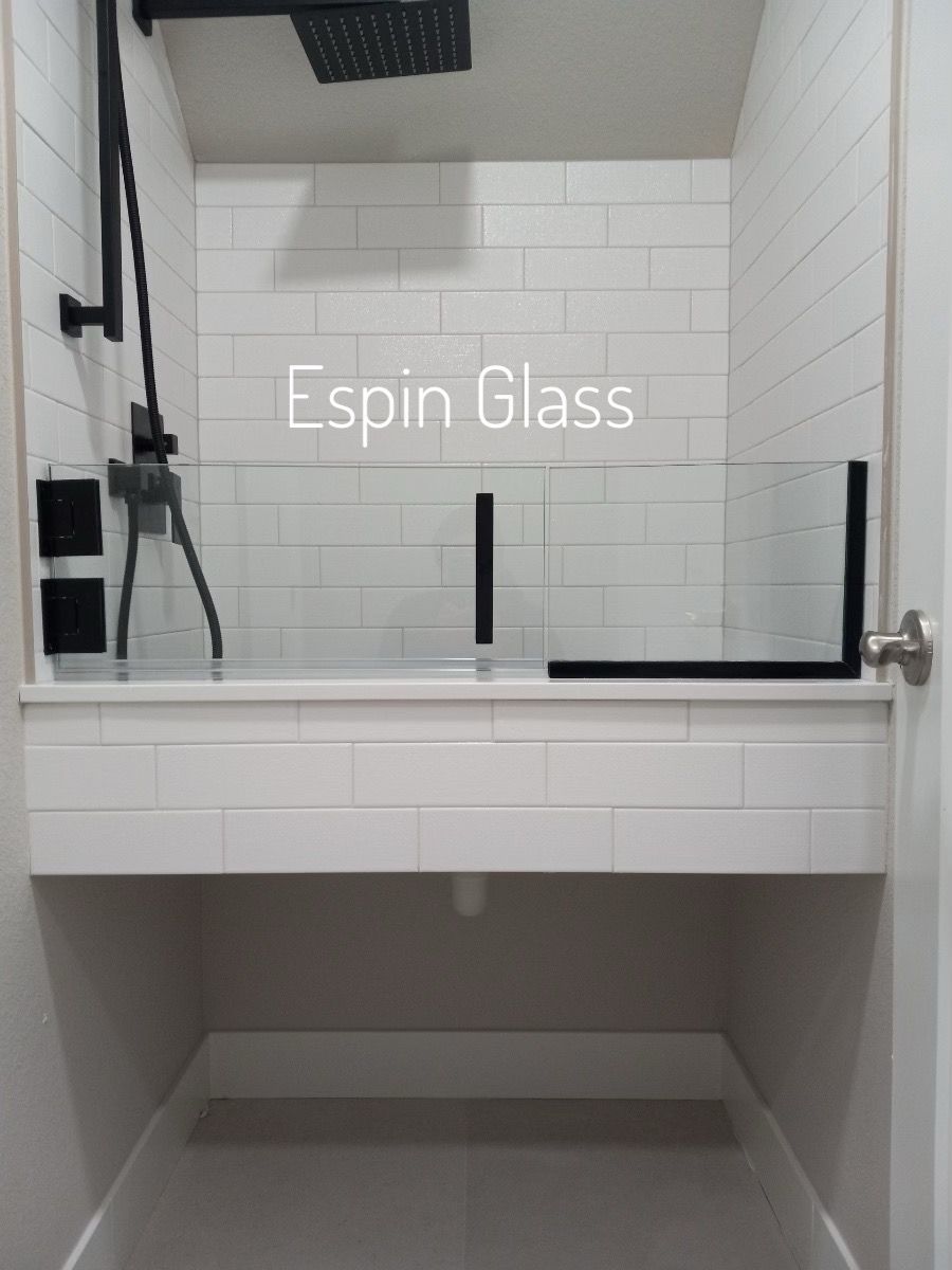 Accessible bathroom with black shower fixtures, glass divider, white subway tile, and gray floor.