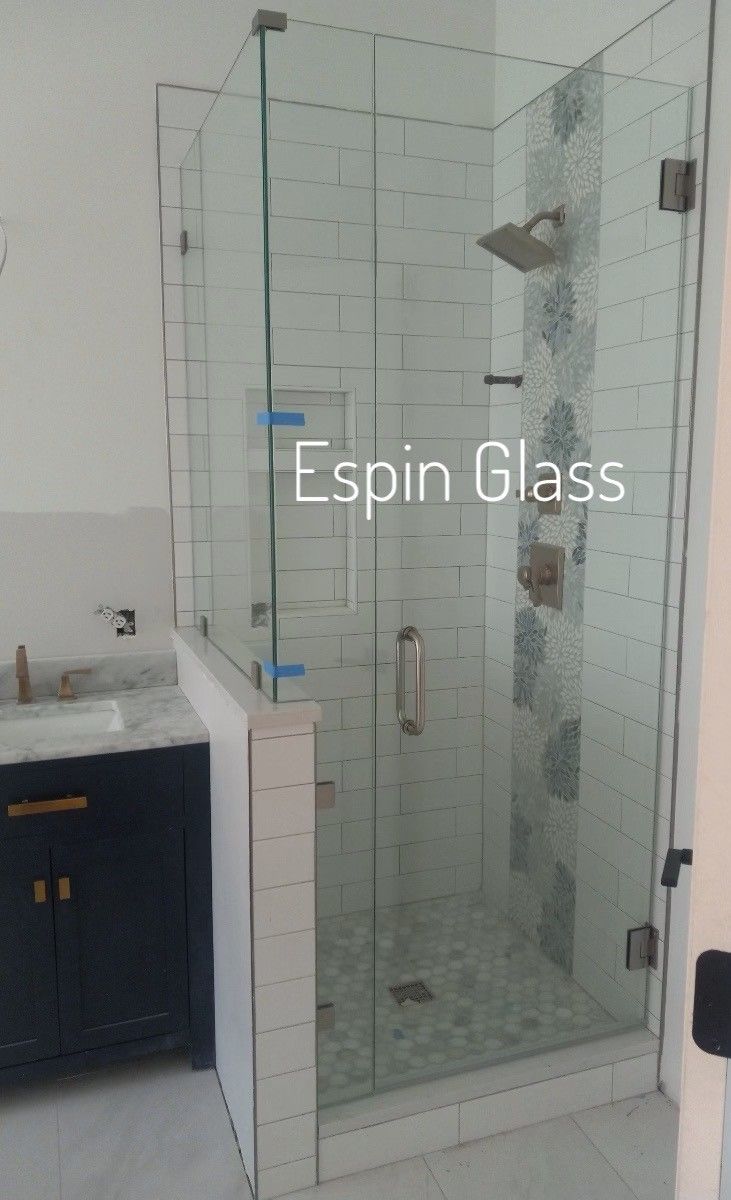 Glass shower enclosure with door and side panel, tiled interior, bathroom setting.