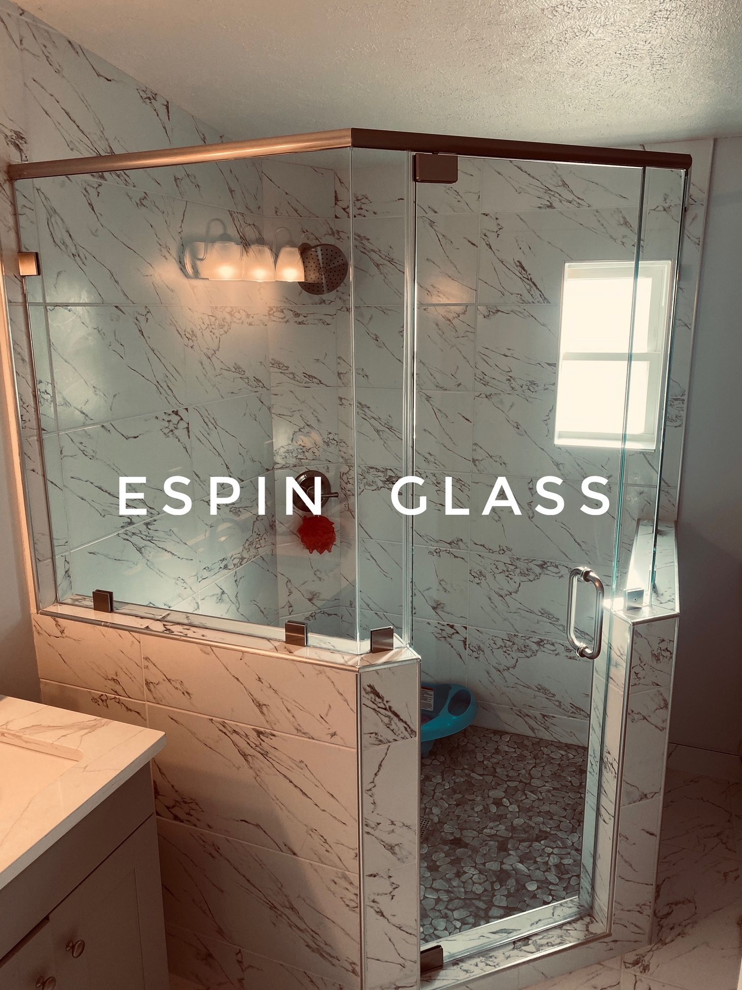 Glass shower enclosure with marble tiles and brass hardware.