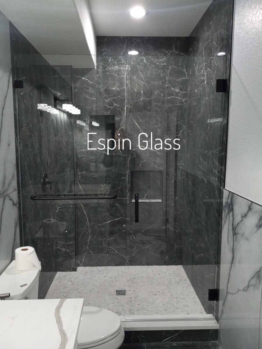 Modern bathroom with gray marble walls and glass shower enclosure; toilet visible.