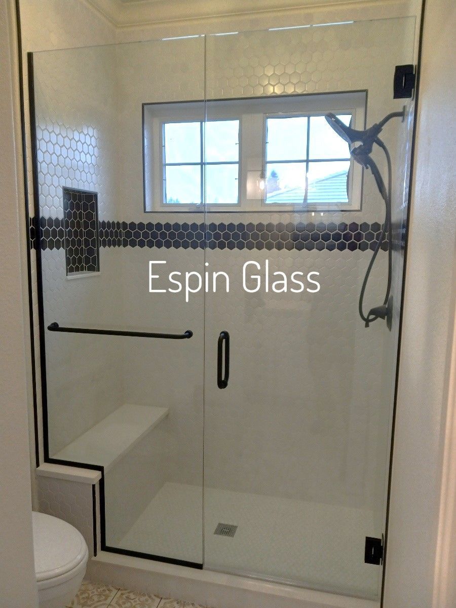 Glass shower enclosure with black trim and hardware, white and dark blue mosaic tile accent.