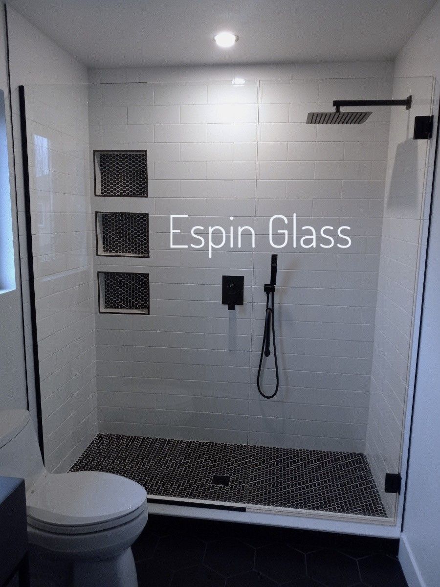 Modern bathroom with a glass shower, black fixtures, and black and white tiling.