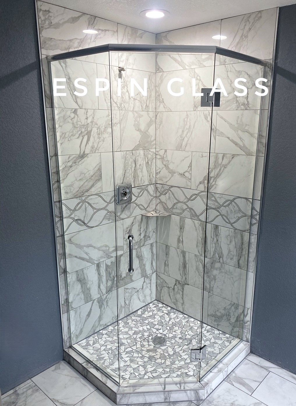 Corner shower with marble-patterned walls, glass doors, and a mosaic floor.